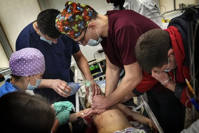 Medics perform CPR on a girl at the city hospital of Mariupol, who was injured during shelling in a residential area in eastern Ukraine, Sunday, February 27, 2022. The girl did not survive. (Photo by Evgeniy Maloletka/AP Photo)