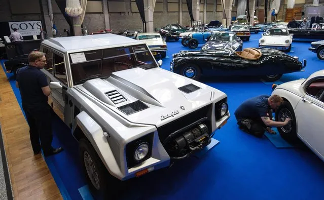 A man inspects a 1991 Lamborghini LM02 (estimate £140,000 - £180,000) as a worker polishes another car on display inside the Royal Horticultural Halls on April 11, 2017 in London, England. (Photo by Jack Taylor/Getty Images)