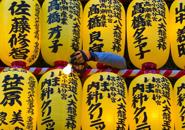 Worker fixes a light bulb to a wall of lanterns during the annual Mitama Festival at the Yasukuni Shrine in Tokyo, Japan, July 13, 2015. (Photo by Thomas Peter/Reuters)