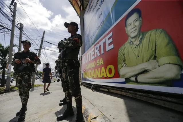 Filipino soldiers stand guard next to the banner dusplaying the likeness of presumptive president-elect Rodrigo Duterte on a street in Davao City, southern Philippines, 16 May 2016. On 15 May 2016, Duterte said that he will urge congress to restore the death penalty and to give security forces a “Shoot-to-kill” order against members of organized crime syndicates. (Photo by Ritchie B. Tongo/EPA)