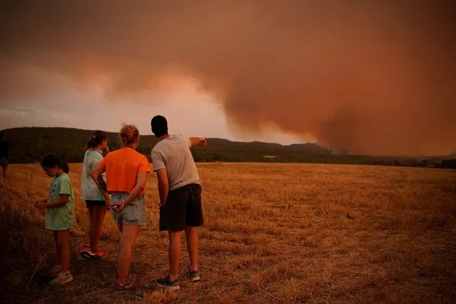 Residents look at wildfire near Tarragona, in the northeastern region of Catalonia, Spain, Sunday, July 25, 2021. Firefighters in northeast Spain are battling a wildfire that has consumed over 1,200 hectares (3,000 acres) of woodland. High temperatures and winds fanned the flames in the rural area. (Photo by Joan Mateu Parra/AP Photo)
