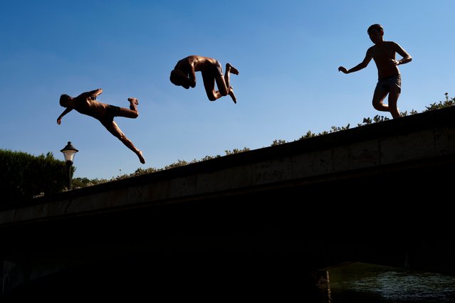 Youngsters jump into a lake in Bucharest, Romania, Tuesday, July 9, 2024 as temperature exceeded 39 degrees Celsius (102.2 Fahrenheit). The national weather forecaster issued an orange warning for the coming week, as temperature is expected to reach 40 degrees Celsius (104 Fahrenheit). (Photo by Vadim Ghirda/AP Photo)