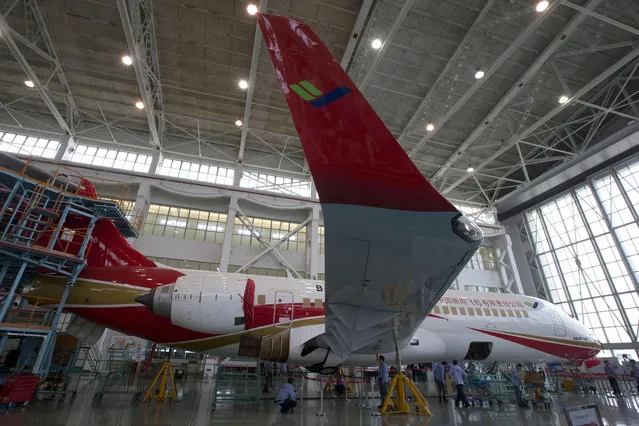 Workers put the finishing touches to a COMAC ARJ21-700 at a final assembly and manufacturing center in Shanghai, China, Wednesday, May 21, 2014. China's state-owned plane maker Comac said Wednesday they were ready to deliver their first regional airliner and were on track to deliver their greater distance-flying narrow-body airplane to customers in 2018. (Photo by Ng Han Guan/AP Photo)