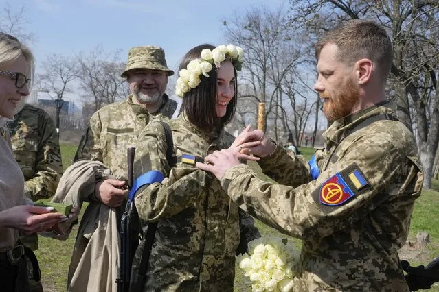 Vyacheslav, a Ukrainian soldier, puts a wedding ring on Anastasia's finger during their wedding ceremony in a city park in Kyiv, Ukraine, Thursday, April 7, 2022. (Photo by Efrem Lukatsky/AP Photo)