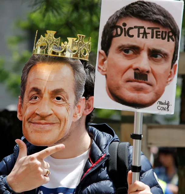 A French student wears a mask and holds a poster depicting French Prime Minister Manuel Valls and former French President Nicolas Sarkozy during a demonstration against the French labour law proposal in Marseille, France, as part of a nationwide labor reform protests and strikes, May 26, 2016. (Photo by Jean-Paul Pelissier/Reuters)
