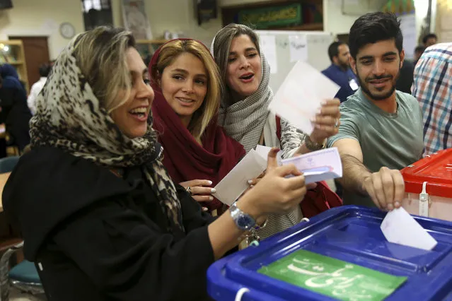 Joyful voters cast their ballots for the presidential election at a polling station in Tehran, Iran, Friday, May 19, 2017. Millions of Iranians voted late into the night Friday to decide whether incumbent President Hassan Rouhani deserves another four years in office after securing a landmark nuclear deal, or if the sluggish economy demands a new hard-line leader who could return the country to a more confrontational path with the West. (Photo by Vahid Salemi/AP Photo)