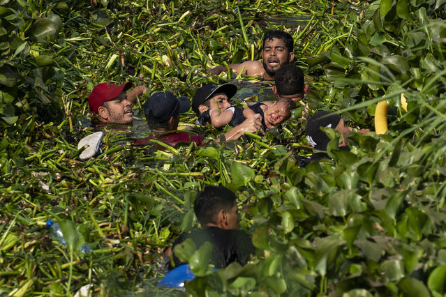 Migrants try to keep a baby from drowning as they cross the Rio Grande River to the United States border as Title 42 expires on May 11, 2023 in Matamoros, Mexico. Title 42 is a Trump-era policy that allows border agents to quickly turn away migrants seeking asylum due to COVID-related concerns. The policy expires at 11:59 pm on May 11, 2023. (Photo by Carolyn Van Houten/The Washington Post)