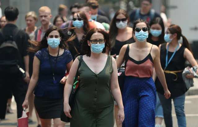 People are seen wearing face masks to protect from smoke haze as they cross a busy city street on December 05, 2019 in Sydney, Australia. Smoke haze continues to hang over the city as more than 50 bushfires continue to burn across New South Wales. (Photo by Don Arnold/Getty Images)