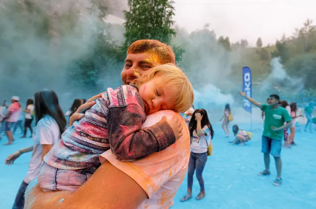 A participant carries his sleeping daughter as he attends the YARKOcross colour run race in Almaty, Kazakhstan, June 5, 2016. (Photo by Shamil Zhumatov/Reuters)