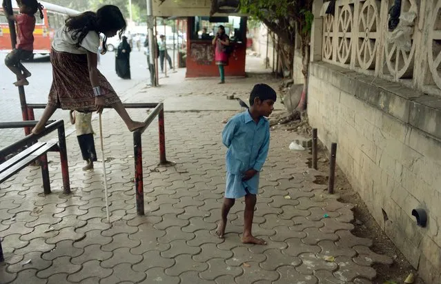 In this photograph taken on May 20, 2014 nine year old Indian boy Lakhan Kale (R) meanders along the pavement in Mumbai. (Photo by Punit Paranjpe/AFP Photo)