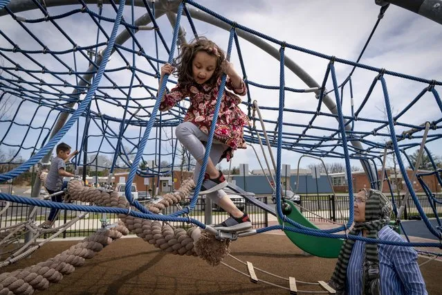 Hanzala Safi and her brother Mohammad climb a rope course next to their grandmother Fawzi Safi at a playground in Alexandria, Virginia on May 3, 2022. The family was evacuated from Afghanistan and is trying to make a new life in the US, while in immigration limbo. (Photo by Jacquelyn Martin/AP Photo)