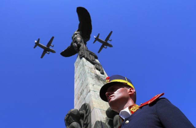 A formation of two military transport aircrafts C-27J Spartan belonging to the Romanian Air Force fly over the Statue of Air Heroes, that is flanked by a honor guard soldier (R), in Bucharest, Romania, 20 July 2023. The Romanian Aviation and Air Force Day is celebrated every year on 20 July, when the Holy Prophet Elijah, considered the spiritual protector of the pilots, is celebrated by the Romanian orthodox believers. (Photo by Robert Ghement/EPA)