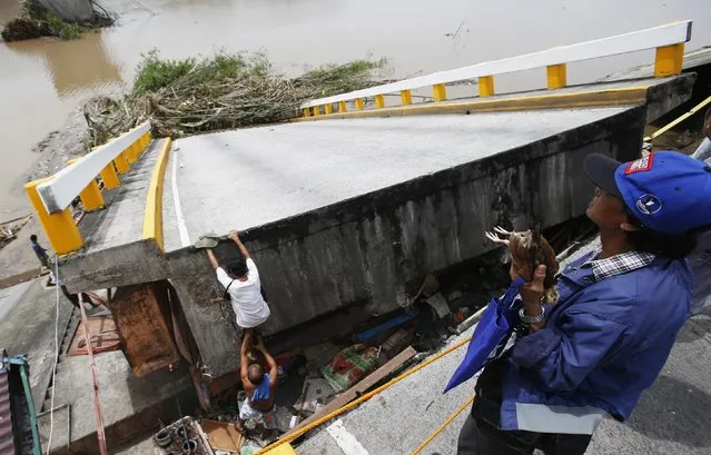 A resident climbs on a bridge destroyed during the onslaught of Typhoon Rammasun, (locally named Glenda) in Batangas city south of Manila, July 17, 2014. The Philippines set to work clearing debris, reconnecting power and rebuilding flattened houses on Thursday after a typhoon swept across the country killing 38 people, with at least eight missing, rescue officials said. (Photo by Erik De Castro/Reuters)