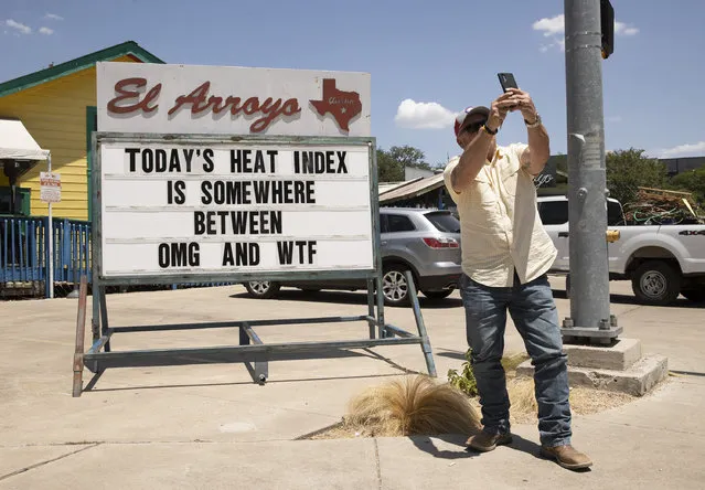 Mitchell Clearman takes a photo of a sign at El Arroyo restaurant in Austin, Texas, on a hot afternoon, Thursday, June 23, 2022. A heat wave that's already lasted more than a week keeps on baking the US, Asia and even the Arctic. (Photo by Jay Janner/Austin American-Statesman via AP Photo)