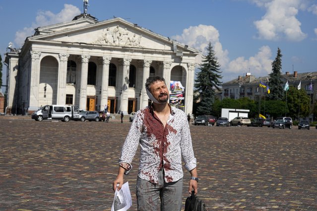 An injured man walks in Krasna square with the Taras Shevchenko Chernihiv Regional Academic Music and Drama Theatre in the background, after a Russian attack, in Chernihiv, Ukraine, Saturday, August 19, 2023. (Photo by Efrem Lukatsky/AP Photo)