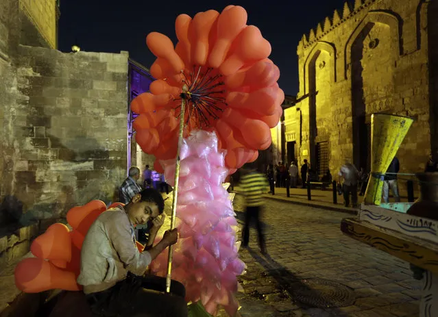 In this Monday, May 18, 2015 photo, An Egyptian cotton candy and balloon vender waits for clients at el-Moez Street in historical Fatimid Cairo, in Egypt. The Arab world's most populated capital city, Cairo is often referred to as an open-air museum of Islamic antiquities and the city of 1,000 minarets. But its rich history and contributions to Islamic art has languished. (AP Photo/Amr Nabil)