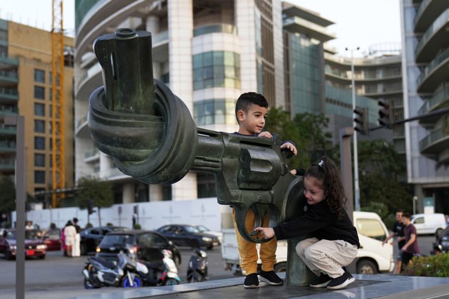 Hussein and Zahraa, 3, displaced Lebanese twins who fled with their parents from their village of Mais al-Jabal in south Lebanon amid the ongoing Hezbollah-Israel war, play on a gun with a twisted barrel statute, symbolizing anti-violence, in Beirut, Lebanon, Thursday, October 31, 2024. (Photo by Hussein Malla/AP Photo)