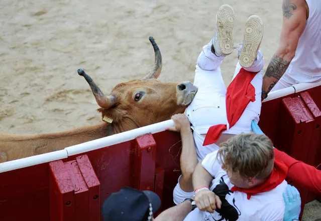 A reveller is tossed by a wild cow after the first running of the bulls at the San Fermin festival in Pamplona, northern Spain, July 7, 2016. (Photo by Eloy Alonso/Reuters)