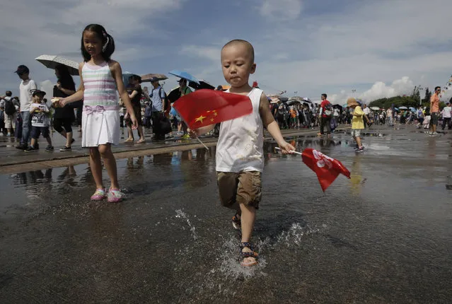 A boy plays in the rain puddles during the open day of Chinese People's Liberation Army (PLA) Navy Base at Stonecutter Island, in Hong Kong to mark the 19th anniversary of the Hong Kong handover to China, Friday, July 1, 2016. (Photo by Kin Cheung/AP Photo)