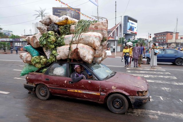 A motorist drives a car overloaded with vegetables and fruit on a street in Yaounde on July 25, 2022, prior to the French president's visit. (Photo by Ludovic Marin/AFP Photo)
