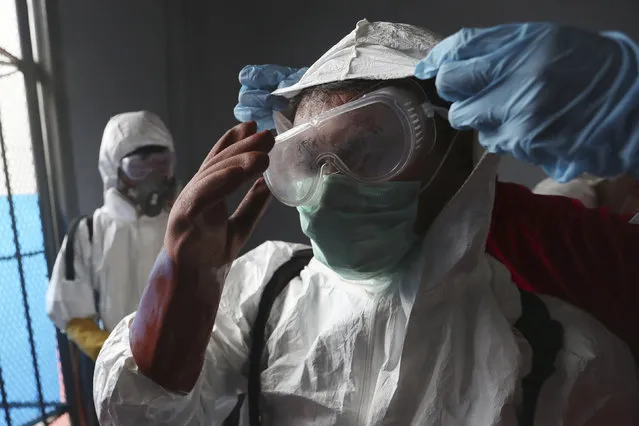 A member of Indonesian Red Cross receives assistance from a colleague to adjust his protective suit as they prepare to disinfect Cipinang Prison compound to prevent the spread of new coronavirus outbreak, in Jakarta, Indonesia, Friday, March 20, 2020. The vast majority of people recover from the new coronavirus. According to the World Health Organization, most people recover in about two to six weeks, depending on the severity of the illness. (Photo by Achmad Ibrahim/AP Photo)