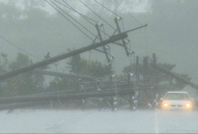 A car passes by power lines downed by the high winds from Typhoon Koinu in Taiwan's southern Pingtung County on October 5, 2023. Typhoon Koinu grazed the southern edge of Taiwan on October 5, blanketing the region in torrential rain and bringing record-breaking winds of more than 340 kilometres an hour to an outlying island. (Photo by Sean Chang/AFP Photo)