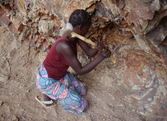 In this photo taken on Thursday, June 16, 2016, a women rock-crusher hits rocks with a hammer in a quarry in Maroua, Cameroon. In a northern Cameroon town menaced by food insecurity and suicide bombers, women as old as 85 are spending long, grueling days crushing rocks into gravel to earn a living. The dangerous, sometimes fatal work often pays no more than $2 per day. (Photo by Joel Kouam/AP Photo)