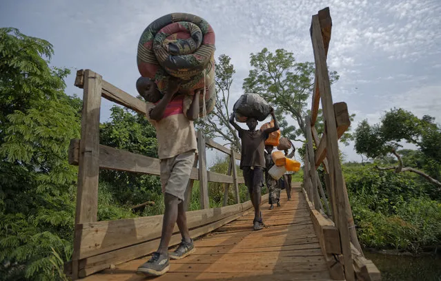 In this Thursday, June 8, 2017 file photo, from left to right, South Sudanese refugees Thomas Wani, 12, brother Peter Lemi, 14, mother Rose Sunday, and father Julius Lezu, cross a wooden bridge from South Sudan to Uganda at the Busia crossing, near Kuluba, in northern Uganda. (Photo by Ben Curtis/AP Photo)