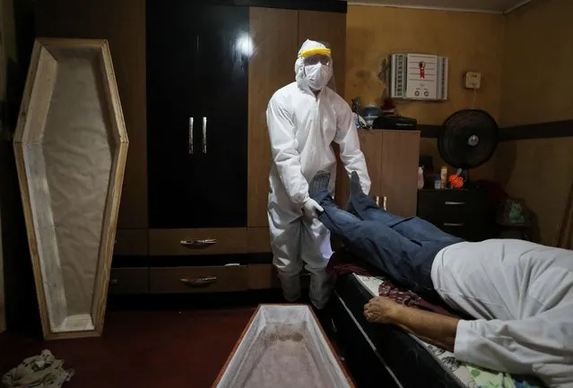 A worker of the Funeral SOS, wearing protective clothing, prepares to remove the body of Antonio Freitas, at his house, amid the coronavirus disease (COVID-19) outbreak, at Tancredo Neves neighborhood in Manaus, Brazil on May 7, 2020. (Photo by Bruno Kelly/Reuters)