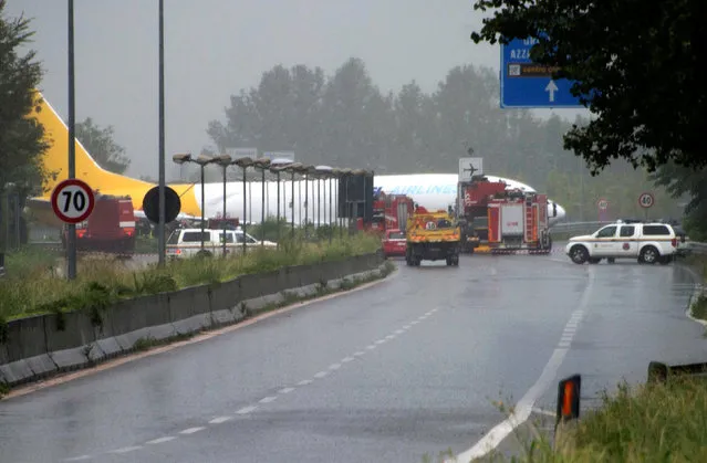 A firefighter stands in front of a cargo plane that exited the runway after landing and sliding onto a local road in Orio al Serio, Italy, August 5, 2016. (Photo by Reuters/Stringer)