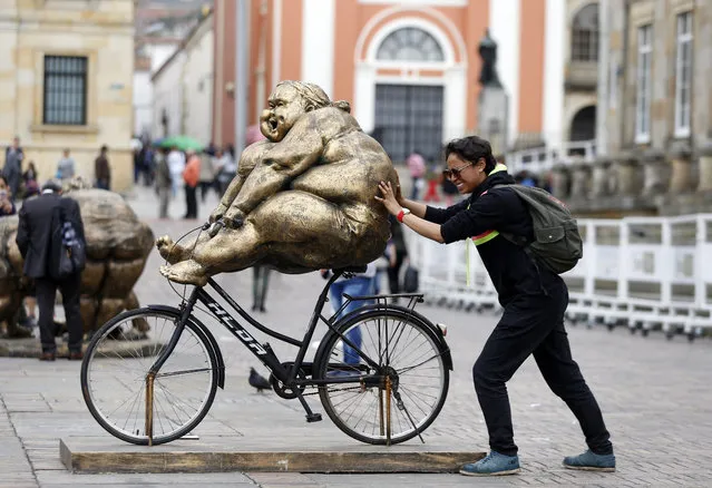 In this November 2, 2017 photo, a woman poses for a photo with a Chubby Women sculpture by Chinese artist Xu Hongfei in an open-air exhibition at Bolivar Square in Bogota, Colombia. (Photo by Fernando Vergara/AP Photo)