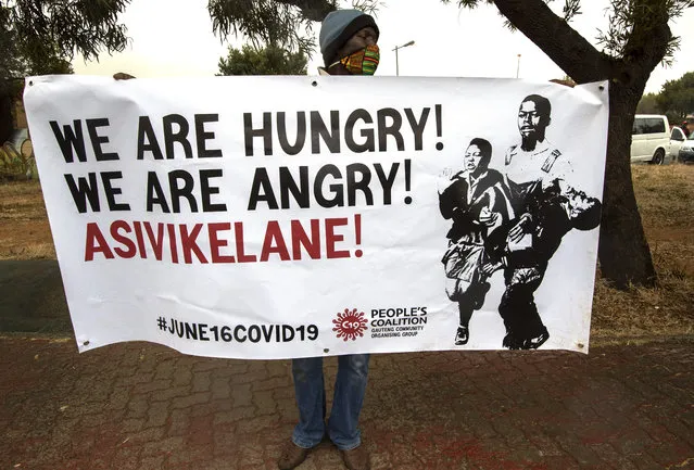 A man holds a poster written “we are hungry, let's protect each other” to mark the country's Youth Day holiday in Soweto, South Africa, Tuesday, June 16, 2020. Nearly 200 young South Africans, wearing face masks and keeping a distance, marked the country's Youth Day holiday, the 44th anniversary of the 1976 Soweto students' uprising which helped to bring about the end of the country's previous regime of racist, minority rule. (Photo by Themba Hadebe/AP Photo)