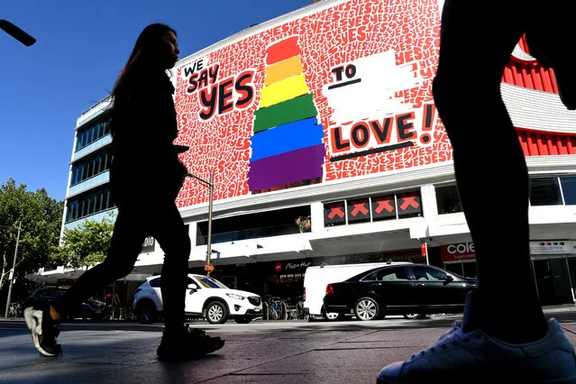 People walk past a giant billboard in Sydney's Kings Cross district promoting the “yes” vote for same-s*x marriage on November 14, 2017. (Photo by William West/AFP Photo)