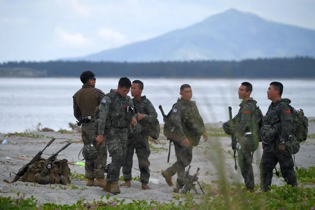 A US marine (L) shares a drink with his South Korean comrades during a joint amphibious landing exercise with their Philippine counterparts at a beach facing the South China Sea in San Antonio town, Zambales province on October 7, 2022. (Photo by Ted Aljibe/AFP Photo)