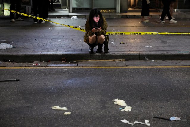 A woman uses a phone near the scene where many people died and were injured in a stampede during a Halloween festival in Seoul, South Korea on October 30, 2022. (Photo by Kim Hong-ji/Reuters)