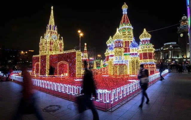 Visitors walk in front of an illuminated replica of The Kremlin and St. Basil Cathedral built for the forthcoming holiday season outside a shopping mall in Moscow, Russia on November 24, 2017. (Photo by Mladen Antonov/AFP Photo)