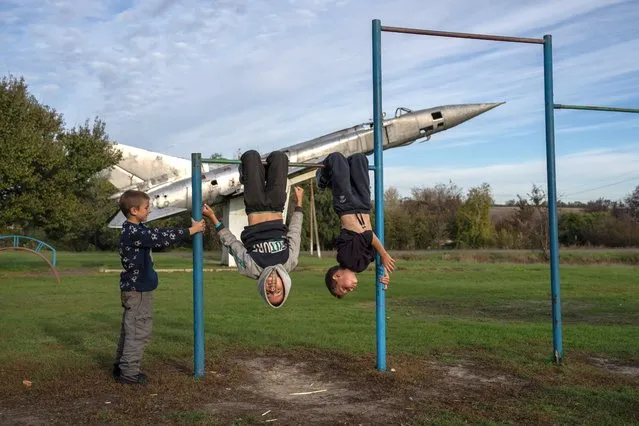 Boys swing on bars in a play park next to a life-size replica of a Soviet-era Sukhoi Su-15 fighter jet on October 19, 2022 in Shostakivka, Donetsk oblast, Ukraine. Russia's president Vladimir Putin today imposed martial law on the four Ukrainian regions occupied by Russian forces as large numbers of civilians were being moved out of the Kherson area ahead of a Ukrainian offensive. (Photo by Carl Court/Getty Images)