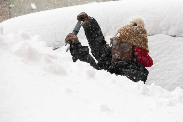 Zaria Black, 24, from Buffalo, clears off her car as snow falls Friday, November 18, 2022, in Buffalo, N.Y.  A dangerous lake-effect snowstorm paralyzed parts of western and northern New York, with nearly 2 feet of snow already on the ground in some places and possibly much more on the way. (Photo by Joshua Bessex/AP Photo)