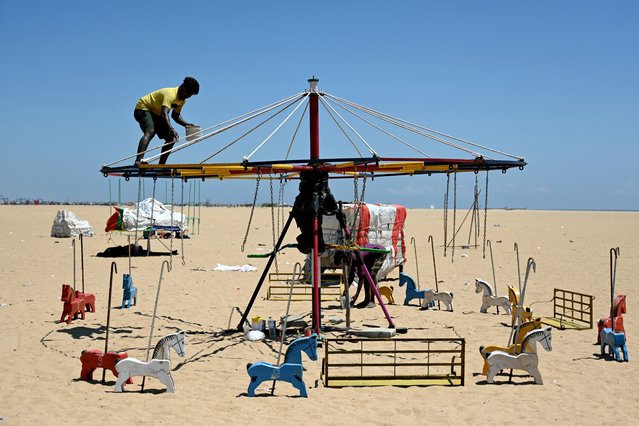 Workers paint a merry-go-round during a hot afternoon, at Marina beach in Chennai on March 19, 2025. (Photo by R.Satish Babu/AFP Photo)