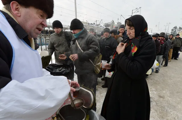 Homeless people  queue to get free hot food organized by social services during frost winter day in  Kiev on December 18, 2012. Nineteen people died of exposure in Ukraine in the last 24 hours amid temperatures of minus 20 degrees Celsius (minus 4 degrees Fahrenheit), bringing the toll this month to 37, the health ministry said Tuesday. (Photo by Sergei Supinsky/AFP Photo)