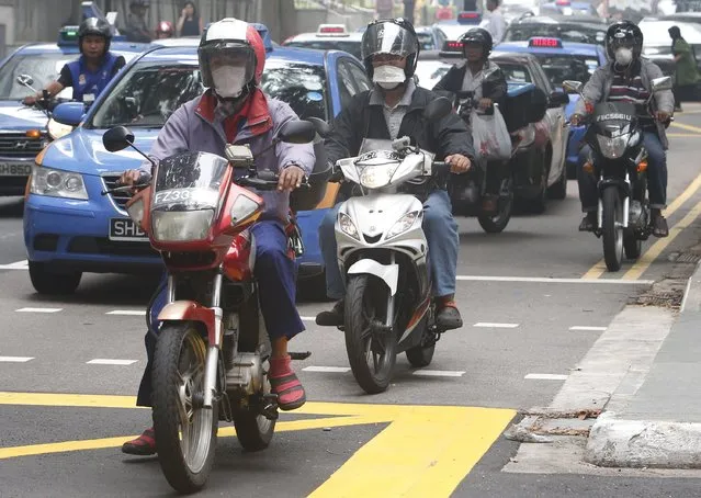 Motorists wearing masks cross a junction during lunch hour at the central business district in Singapore September 29, 2015. (Photo by Edgar Su/Reuters)