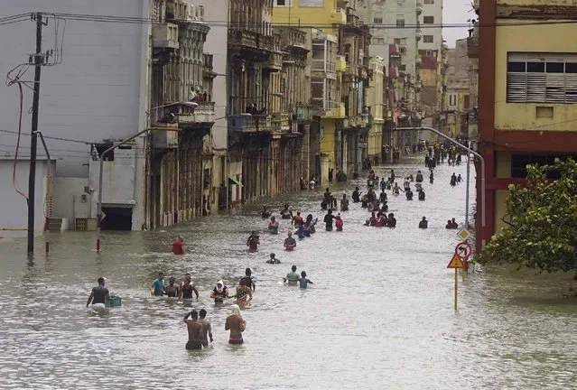 People move through flooded streets in Havana, Cuba, on September 10, 2017, after the passage of Hurricane Irma. The powerful storm ripped roofs off houses, collapsed buildings and flooded hundreds of miles of coastline after cutting a trail of destruction across the Caribbean. (Photo by Ramon Espinosa/AP Photo)