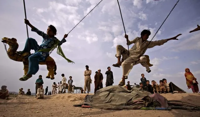 Pakistani children who fled their villages with their families due to fighting between security forces and militants in Pakistan's tribal area of Bajur, enjoy a ride on a merry-go-round at a makeshift entertainment park set up in a slum area on the outskirts of Islamabad, Pakistan, Friday, May 11, 2012. (Photo by Muhammed Muheisen/AP Photo)