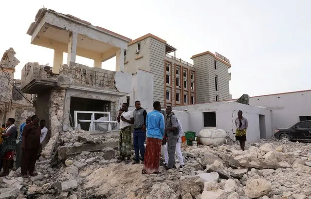 Civilians stand on the rubble of a damaged building at the scene of a militant attack at the Elite Hotel in Lido beach, in Mogadishu, Somalia on August 17, 2020. (Photo by Feisal Omar/Reuters)