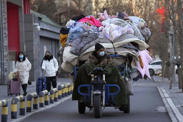 A man wearing a mask transports used quilts and other scavenged cloth material in Beijing, Friday, December 30, 2022. (Photo by Ng Han Guan/AP Photo)