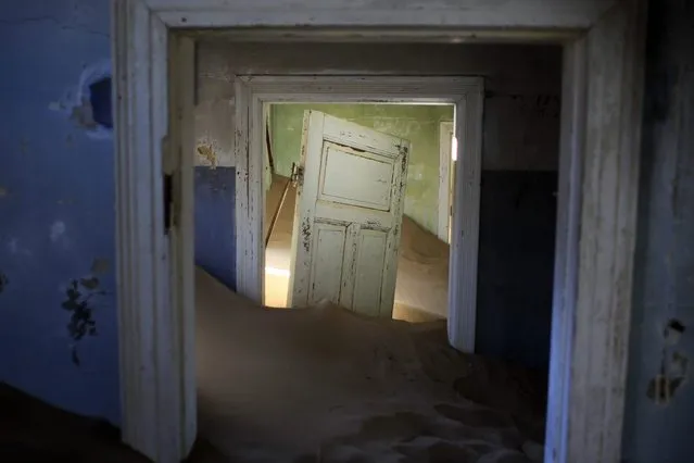 In this July 23, 2013 photo, sand fills an abandoned house in Kolmanskop, Namibia. Kolmanskop, was a diamond mining town south of Namibia, build in 1908 and deserted in 1956. SInce then, the desert slowly reclaims its territory, with sand invading the buildings where 350 German colonists and more than 800 local workers lived during its hay-days of the 1920s. (Photo by Jerome Delay/AP Photo)