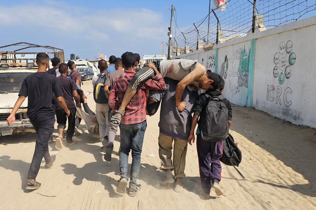 Palestinians carry a wounded man, injured as he was queuing for aid, towards a hospital in Rafah, in the southern Gaza Strip on June 16, 2025. Gaza's civil defence agency said that 20 people waiting for aid in the south of the Palestinian territory were killed by Israeli troops on June 16. (Photo by AFP Photo/Stringer)