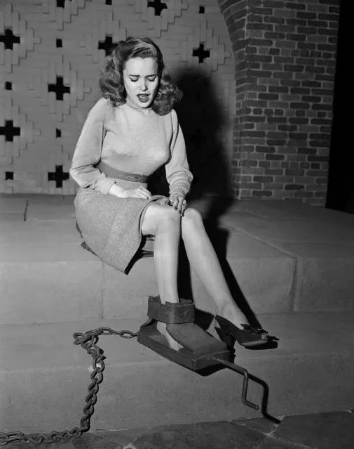 No, actress Lois Collier is not being measured for a new pair of shoes. She's demonstrating a movie studio replica of the “Spanish Boot”, in Hollywood, Los Angeles, Calif., December 30, 1946, used during the middle ages to break feet. Block attached to a crank, which when turned, compresses the shackled foot. (Photo by AP Photo)