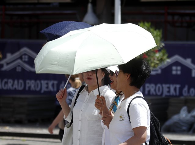 Three women walk with umbrellas, casting shadows in the sun in downtown Zagreb, Croatia, 04 June 2025. In the last few days, Croatia and Zagreb have experienced warmer weather with temperatures exceeding 32 degrees Celsius. (Photo by Antonio Bat/EPA/EFE)