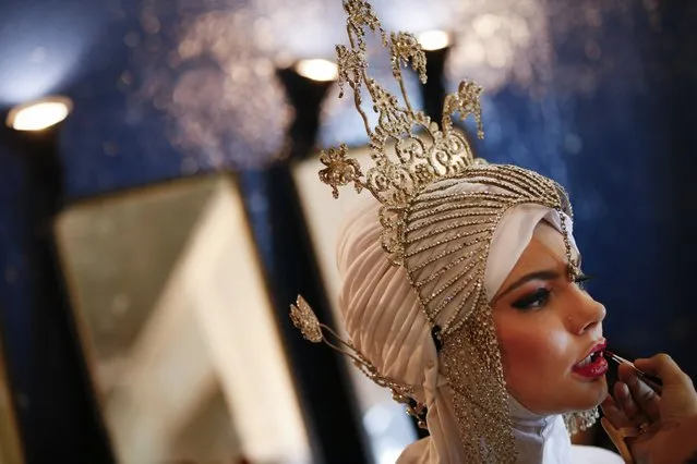 A model has make up applied backstage as she wears a creation from the Calvin Thoo collection during the Islamic Fashion Festival in Kuala Lumpur, Malaysia on Tuesday, November 18, 2014. The Islamic Fashion Festival seeks to raise awareness for Islamic expression, creativity, and culture. (Photo by Vincent Thian/AP Photo)